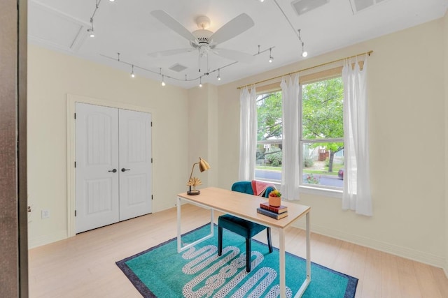 office featuring baseboards, rail lighting, light wood finished floors, and a ceiling fan