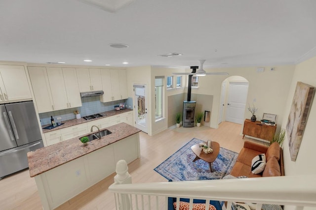 4128 E Lawless St, Austin, TX 78723 - kitchen with stainless steel appliances, a wood stove, light stone countertops, tasteful backsplash, and an island with sink