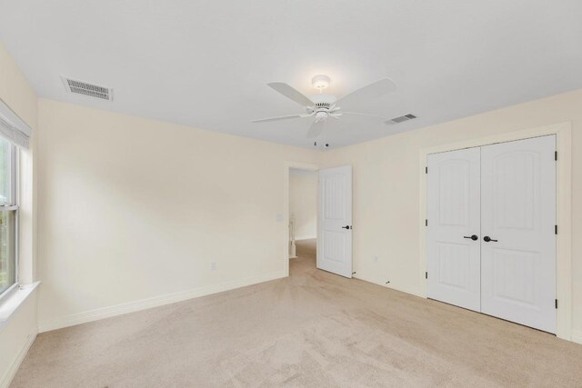 unfurnished bedroom with visible vents, multiple windows, and light colored carpet