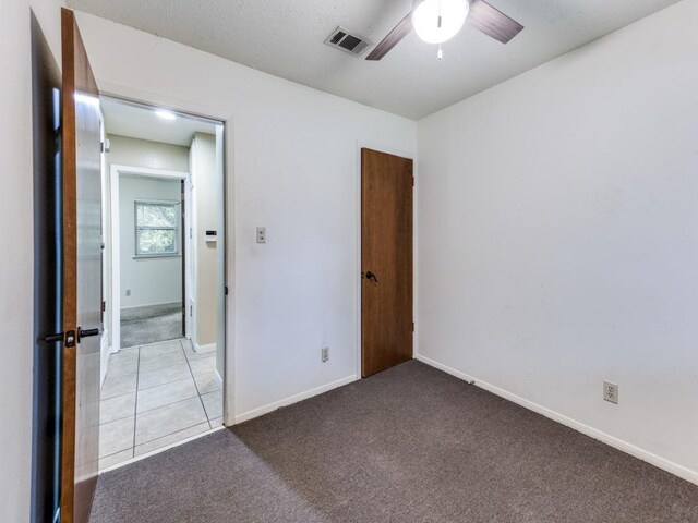 unfurnished bedroom with baseboards, carpet, ceiling fan, and visible vents