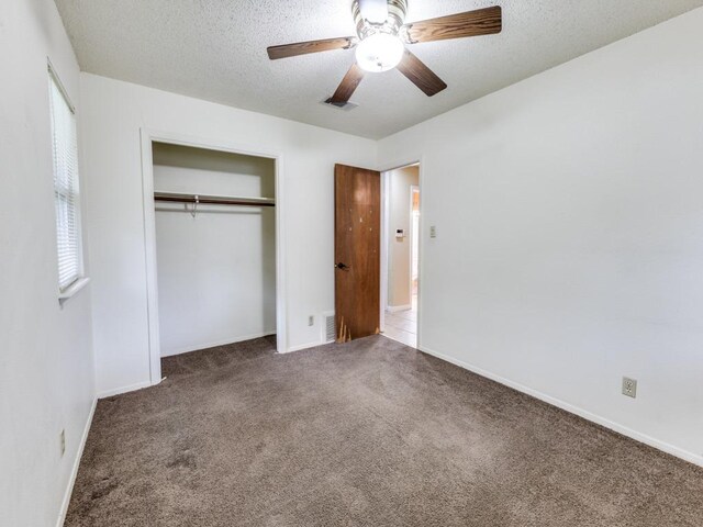 unfurnished bedroom with carpet floors, visible vents, a closet, multiple windows, and a textured ceiling