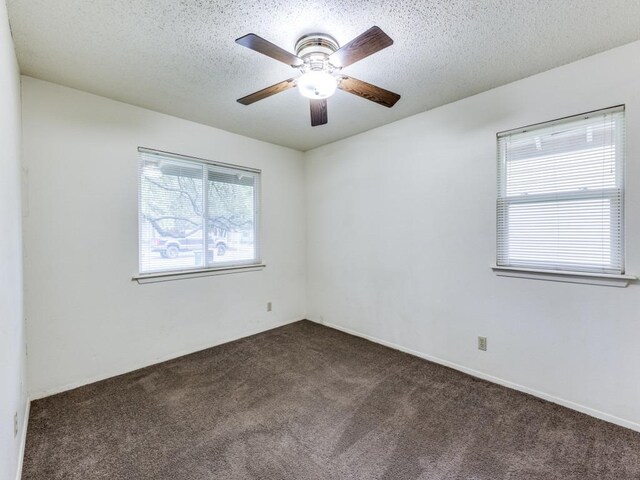 empty room with a ceiling fan, a textured ceiling, and dark colored carpet