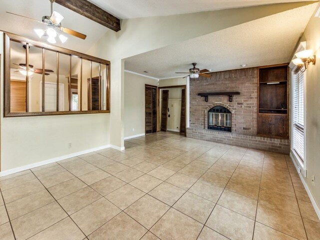unfurnished living room with a brick fireplace, a ceiling fan, baseboards, vaulted ceiling with beams, and light tile patterned floors