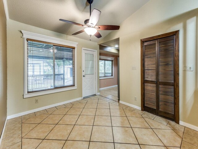 interior space with light tile patterned floors, baseboards, a ceiling fan, and lofted ceiling