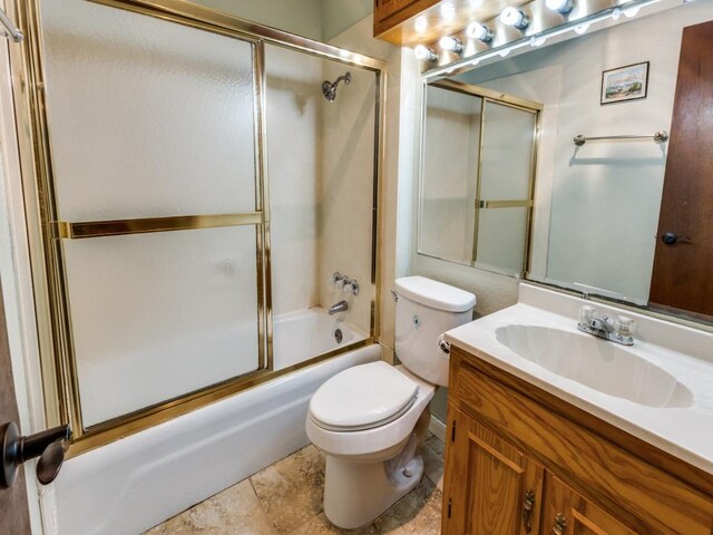 bathroom featuring toilet, shower / bath combination with glass door, and vanity