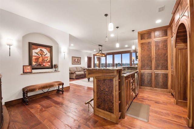kitchen with visible vents, a breakfast bar, stone countertops, baseboards, and hanging light fixtures