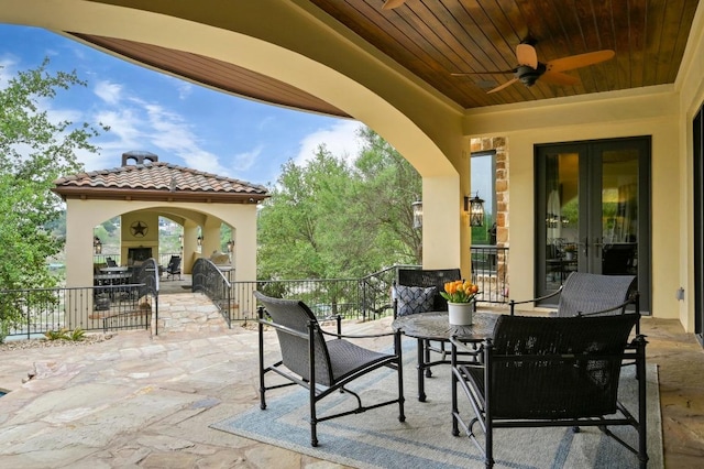 view of patio / terrace featuring ceiling fan, exterior fireplace, and french doors