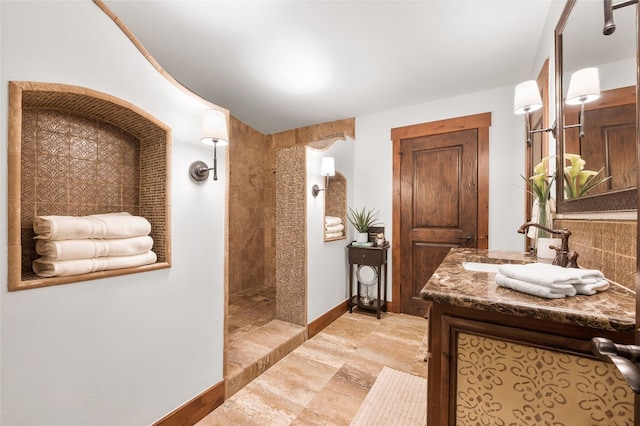 bathroom with vanity, baseboards, and walk in shower