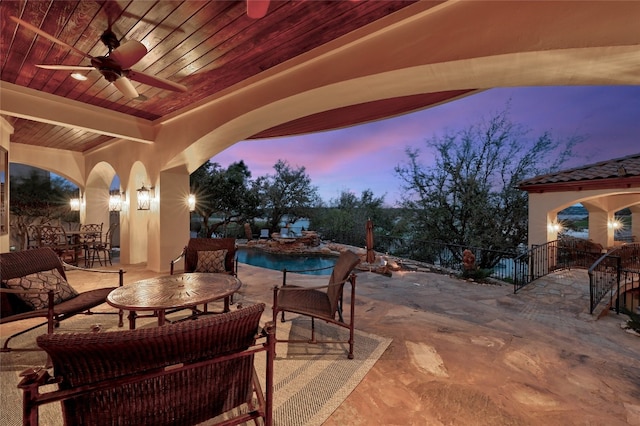 patio terrace at dusk featuring ceiling fan, fence, an outdoor pool, and outdoor dining space