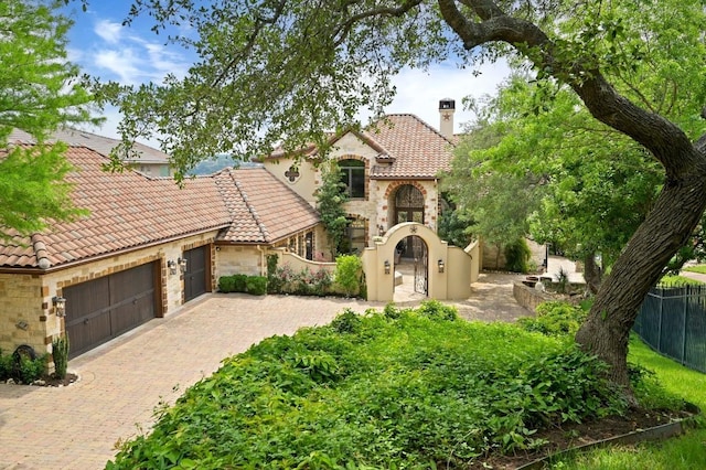 view of front of property with stucco siding, fence private yard, decorative driveway, and stone siding