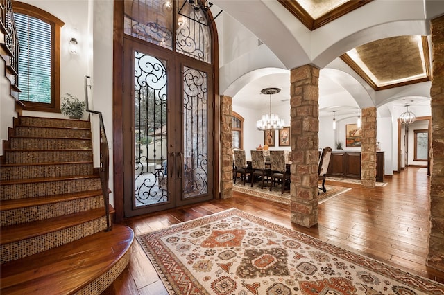 foyer with french doors, arched walkways, decorative columns, and hardwood / wood-style floors