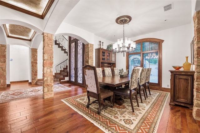 dining space with dark wood-type flooring, arched walkways, visible vents, and an inviting chandelier