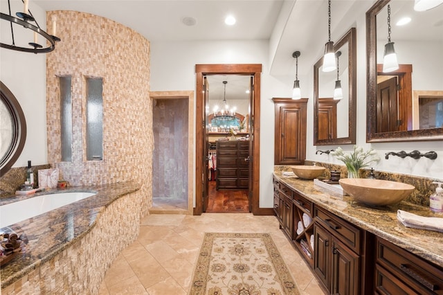 bathroom with double vanity, an inviting chandelier, a sink, and a bath
