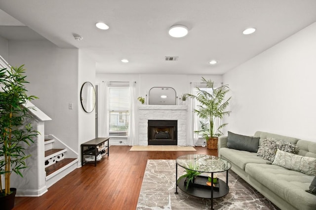 living room with visible vents, wood finished floors, stairway, recessed lighting, and a fireplace with flush hearth