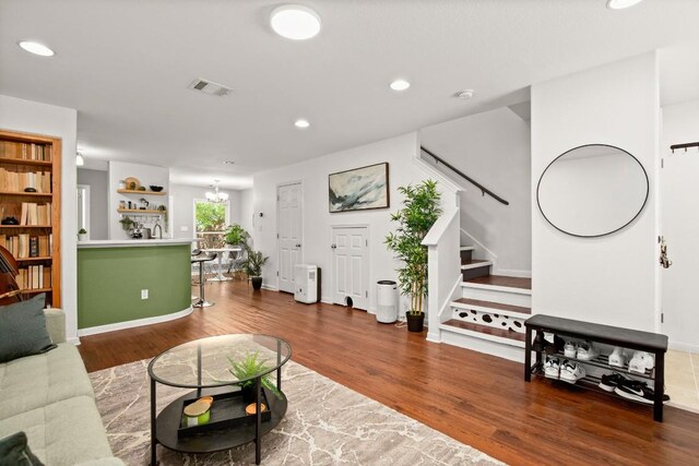 living room with visible vents, stairs, wood finished floors, baseboards, and recessed lighting