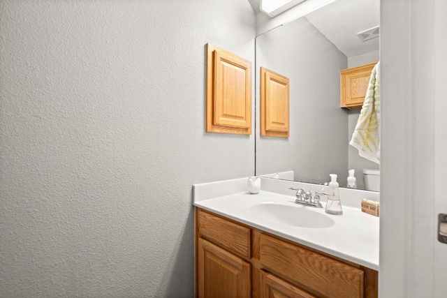 bathroom featuring a textured wall, visible vents, and vanity