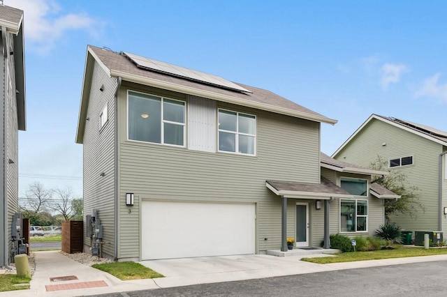 view of front facade with an attached garage, roof mounted solar panels, and driveway