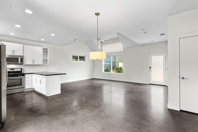 kitchen with a peninsula, dark countertops, open floor plan, finished concrete floors, and stainless steel appliances