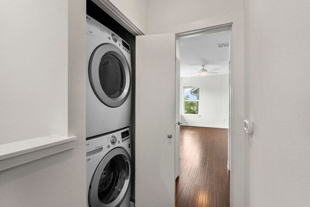 laundry room with laundry area, stacked washing maching and dryer, a ceiling fan, visible vents, and hardwood / wood-style flooring