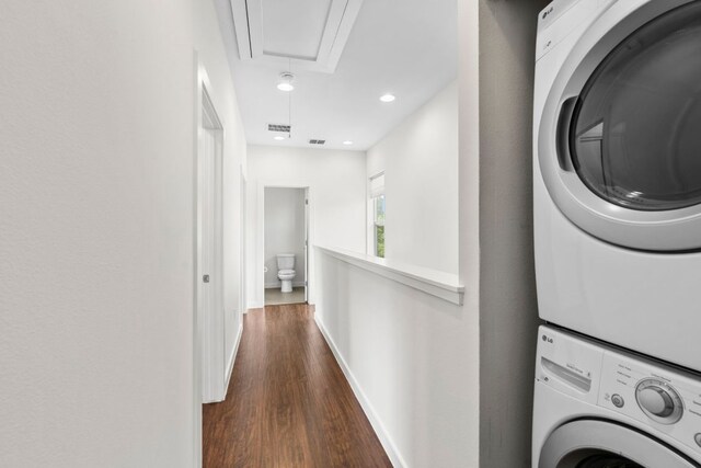 washroom with attic access, stacked washer and dryer, visible vents, baseboards, and dark wood-style floors