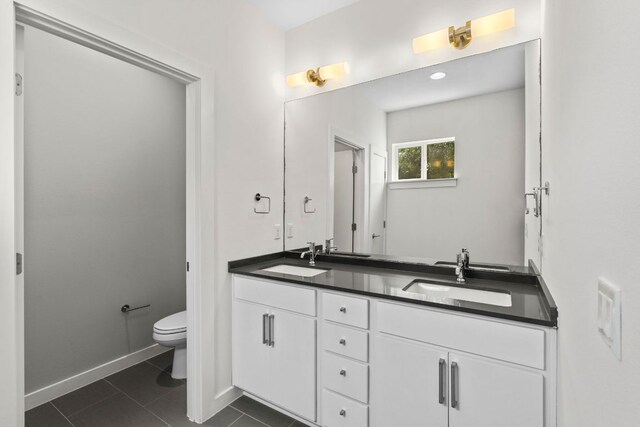 full bath featuring a sink, tile patterned floors, toilet, and double vanity
