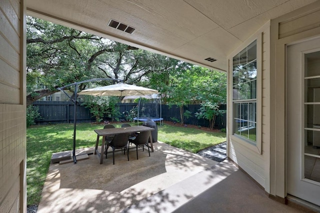 view of patio / terrace with a fenced backyard, a trampoline, visible vents, and outdoor dining space