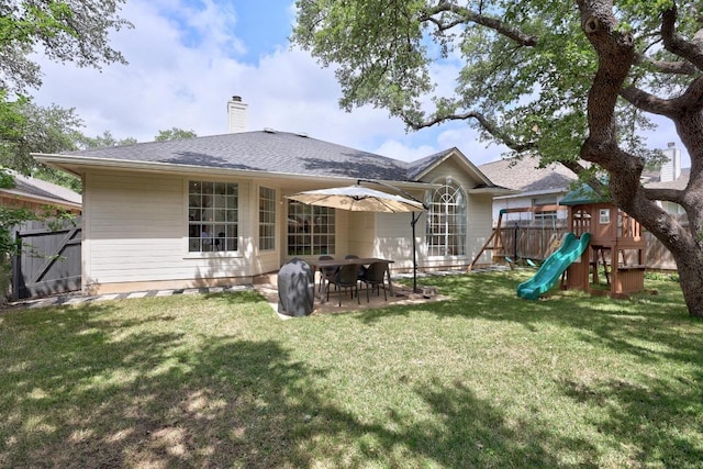 rear view of property featuring fence, a chimney, a patio area, a playground, and a yard