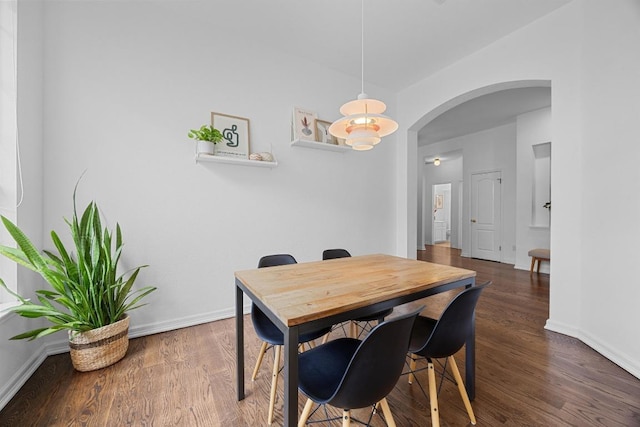 dining room featuring baseboards, arched walkways, and wood finished floors