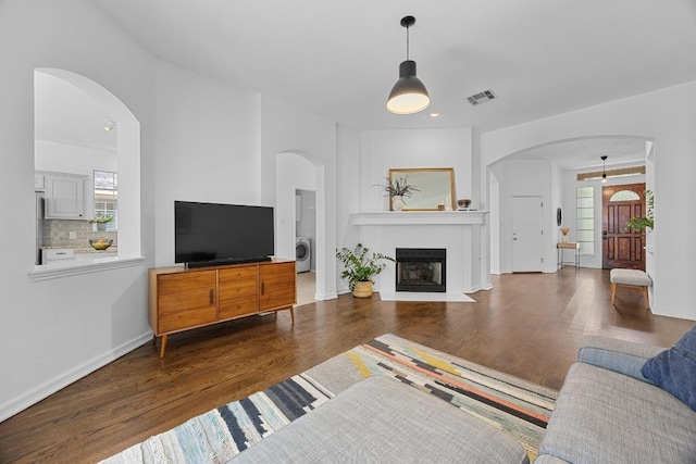 living area featuring washer / dryer, plenty of natural light, wood finished floors, and visible vents