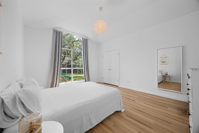 bedroom featuring light wood-style floors, baseboards, and vaulted ceiling