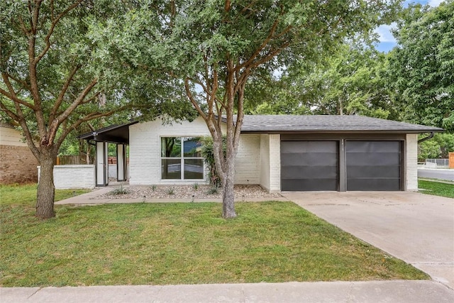 view of front of property with an attached garage, concrete driveway, a front lawn, and brick siding