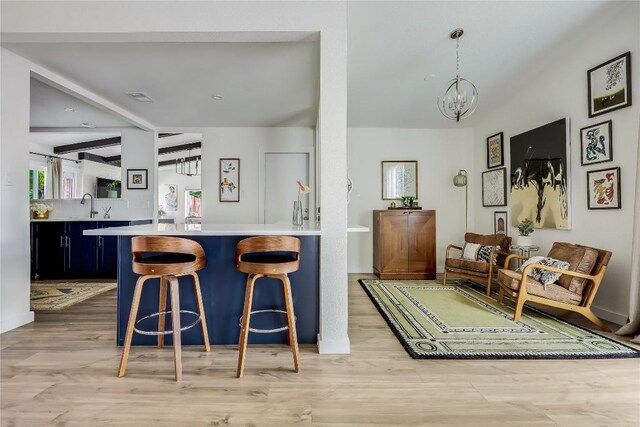interior space featuring visible vents, light countertops, light wood finished floors, a chandelier, and a breakfast bar