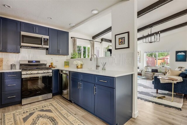 kitchen with a sink, light countertops, stainless steel appliances, and blue cabinetry