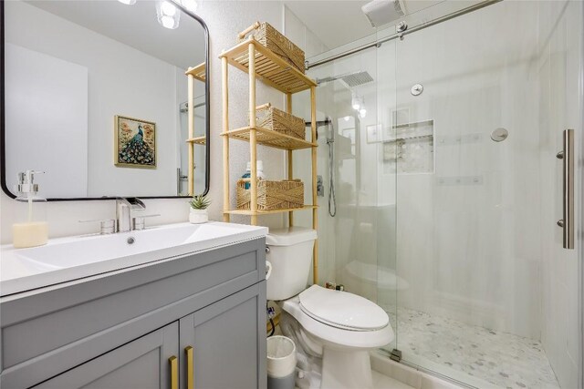 bathroom featuring vanity, a stall shower, and toilet
