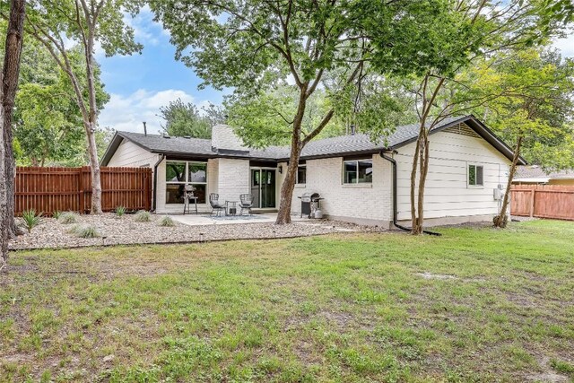 rear view of house featuring fence, a patio, a lawn, and brick siding