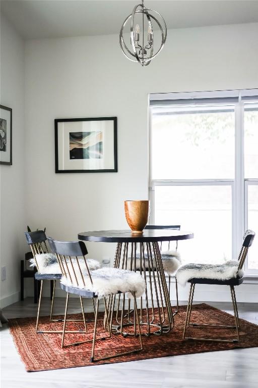 1415 Mearns Meadow Blvd, Austin, TX 78758 - dining room with healthy amount of natural light, wood finished floors, a chandelier, and baseboards