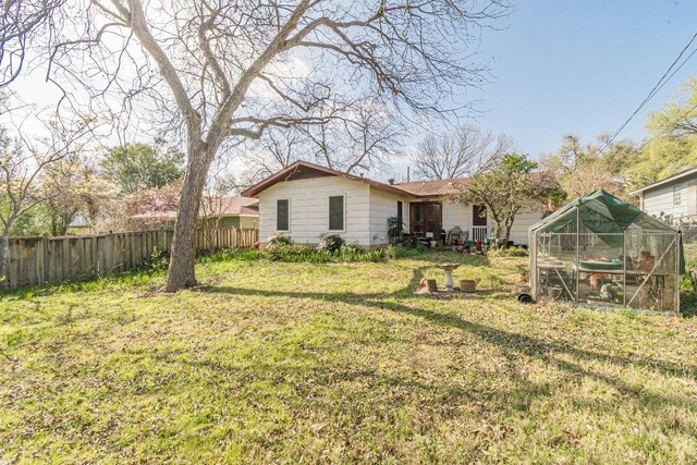 view of yard featuring fence, an outbuilding, and a greenhouse