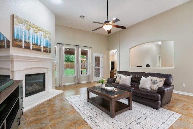 2420 Champions Corner Dr, Leander, TX 78641 - living area with a high ceiling, a ceiling fan, a glass covered fireplace, and stone finish flooring