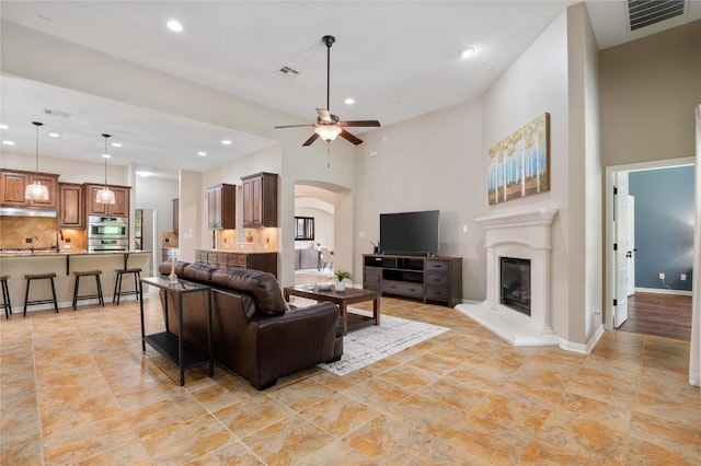 2420 Champions Corner Dr, Leander, TX 78641 - living area featuring recessed lighting, a ceiling fan, a glass covered fireplace, arched walkways, and a high ceiling