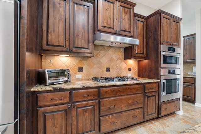 2420 Champions Corner Dr, Leander, TX 78641 - kitchen featuring ventilation hood, stainless steel appliances, decorative backsplash, and light stone counters