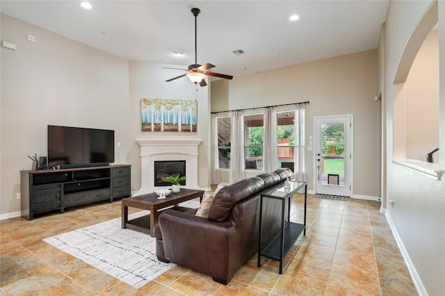 2420 Champions Corner Dr, Leander, TX 78641 - living room with arched walkways, a glass covered fireplace, ceiling fan, baseboards, and recessed lighting