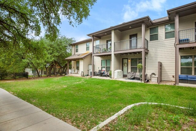 rear view of property featuring a lawn, a patio, and a balcony