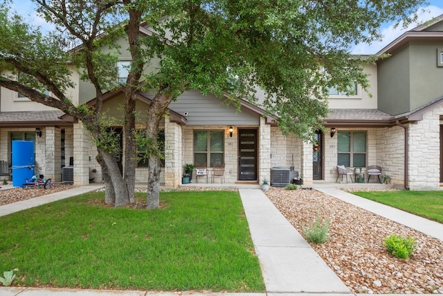 view of front of home with covered porch, cooling unit, a front lawn, stone siding, and stucco siding