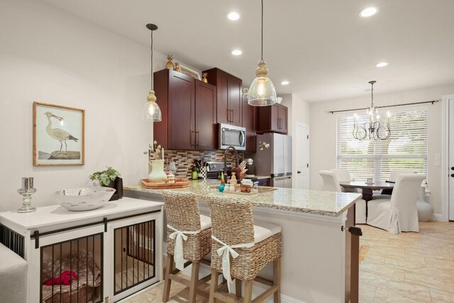 kitchen featuring appliances with stainless steel finishes, a chandelier, a peninsula, recessed lighting, and tasteful backsplash