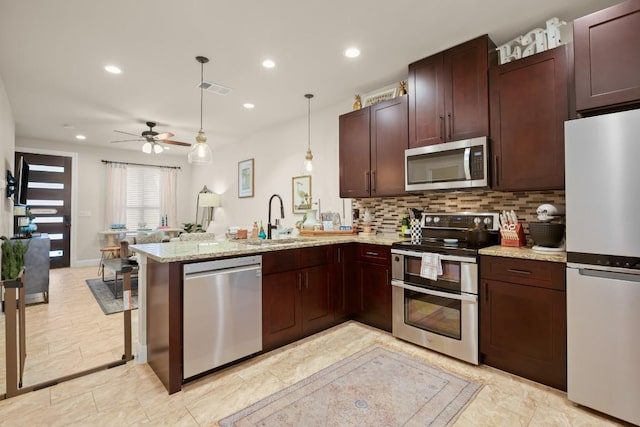581 Demarett Dr, Point Venture, TX 78645 - kitchen featuring appliances with stainless steel finishes, a sink, a peninsula, decorative backsplash, and ceiling fan