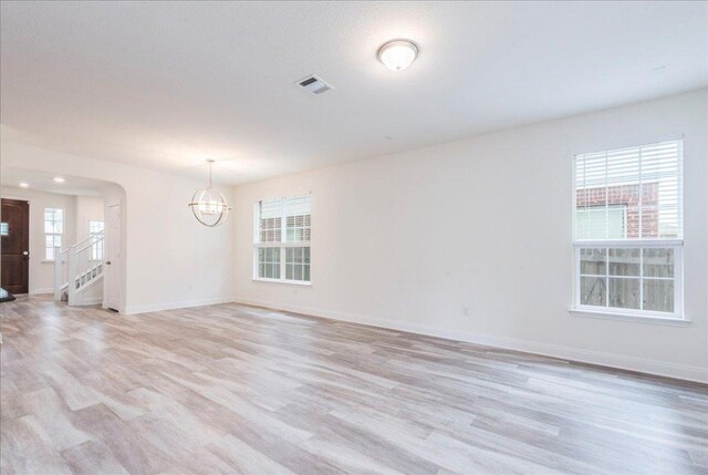 unfurnished room with baseboards, a chandelier, visible vents, and light wood-style floors
