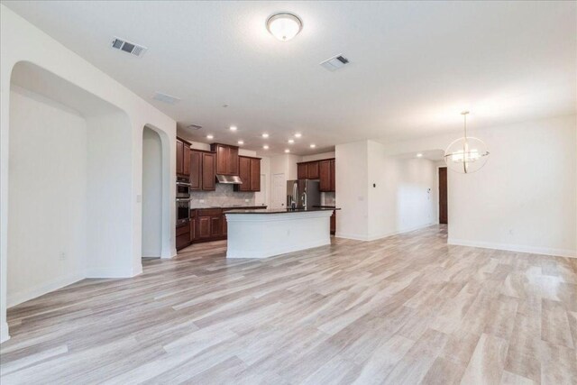 kitchen with dark countertops, visible vents, light wood-type flooring, and open floor plan