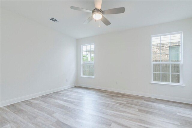 empty room featuring visible vents, a ceiling fan, light wood finished floors, and baseboards