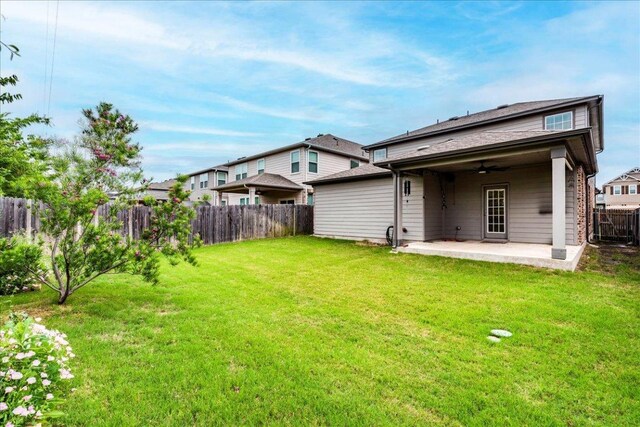 rear view of property featuring a patio, a ceiling fan, a lawn, and a fenced backyard