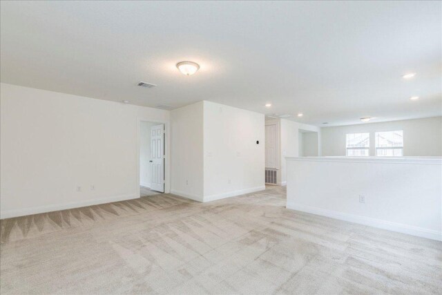 unfurnished room with baseboards, light carpet, recessed lighting, and visible vents